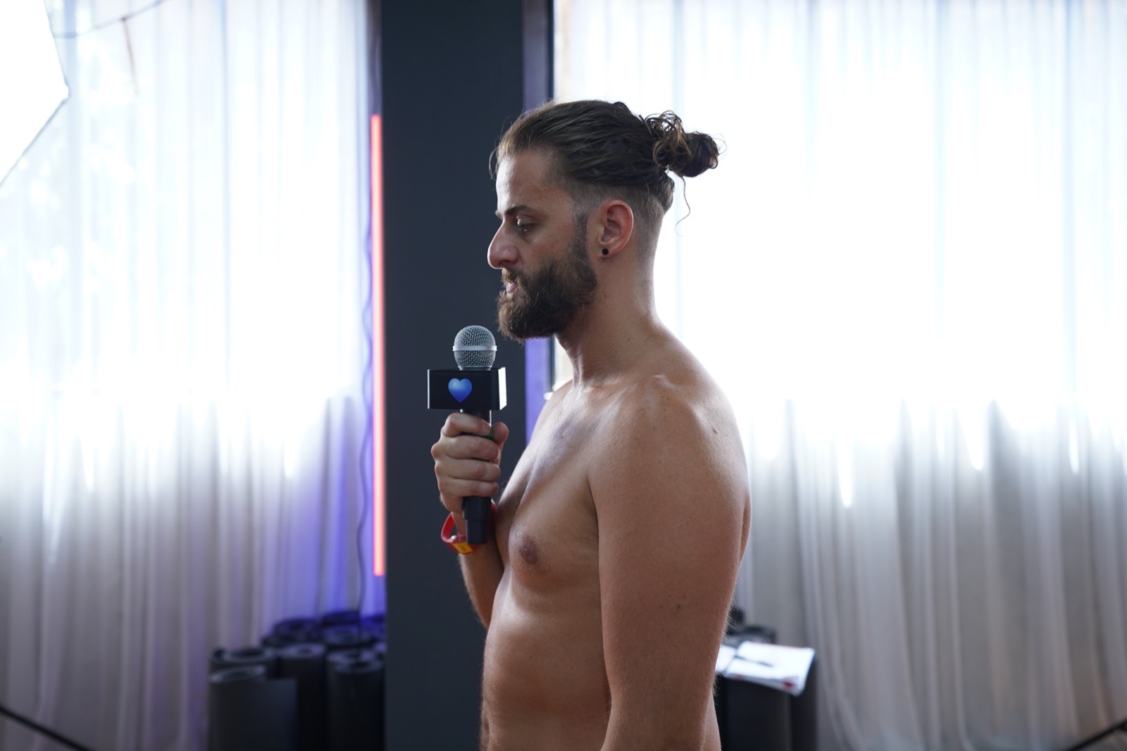 How Many Men Do Yoga? The Rise of Men in the Hot Room Report 5 A bearded male trainee holding a microphone while practising his dialogue delivery in front of the class