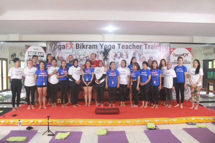 how-many-men-do-yoga-yogafx-teacher-training-intake-group A YogaFX teacher training intake photographed together on stage beneath the Bikram Hot 26 and 2 banner in Bali